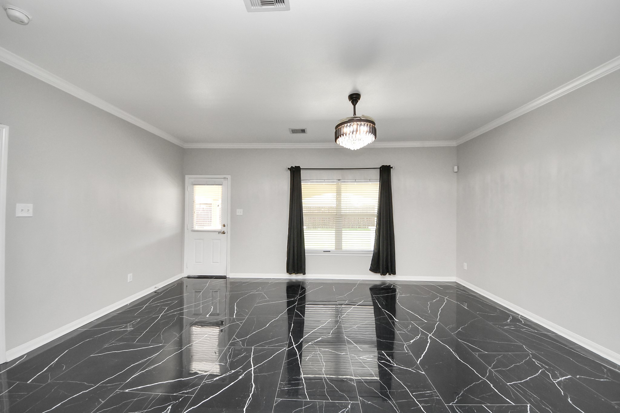6931 Primrose Road Baytown, TX 77521 - Photo 17 of 50 Spacious living room with sleek black marble-style flooring, crown molding, and natural light from large windows overlooking the backyard.