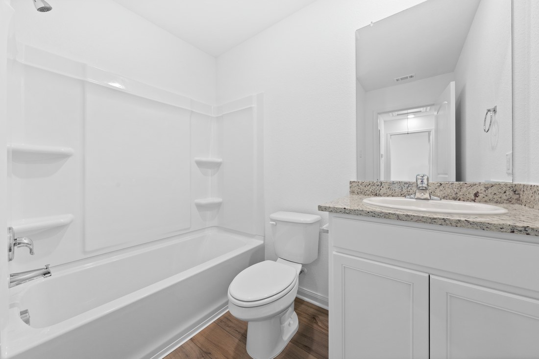 105 Morrison Drive Jarrell, TX 76537 - Photo 6 of 10 a bathroom with a granite countertop toilet a sink and a bathtub