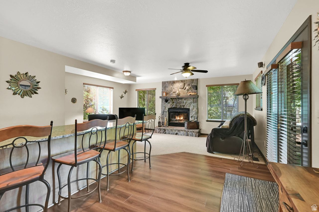 655 Ogden Canyon Road Ogden, UT 84401 - Photo 11 of 50 Living area featuring a stone-faced fireplace with a mantel, wood-finish flooring, and a breakfast bar with a light-toned countertop