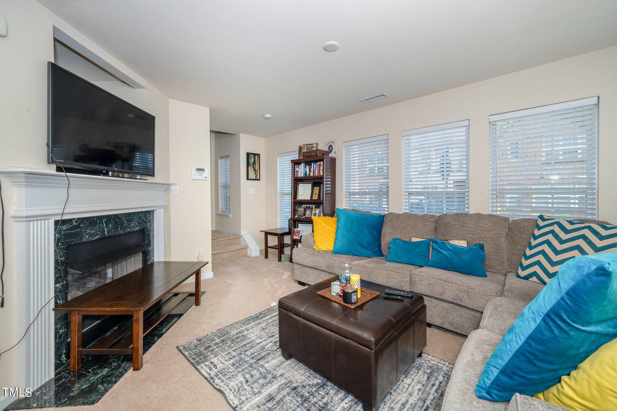9828 Layla Avenue Raleigh, NC 27617 - Photo 6 of 21 a living room with furniture a flat screen tv and a fireplace