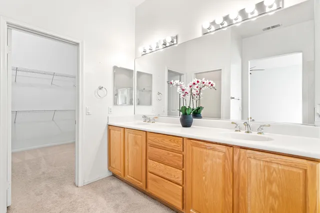 a spacious bathroom with a double vanity sink a mirror and a shower