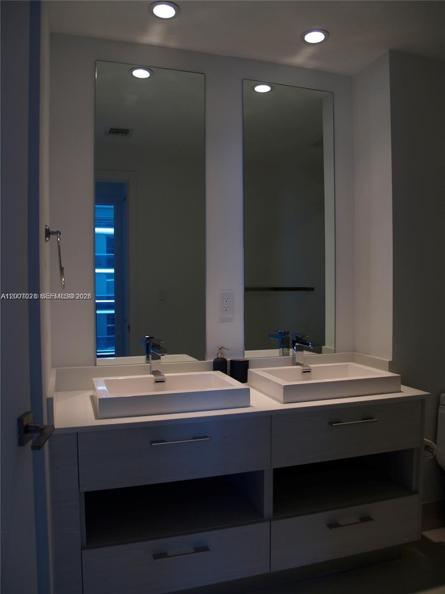 55 Southwest 9th Street, Unit 2502 Miami, FL 33130 - Photo 4 of 27 a bathroom with a double vanity sink and a mirror