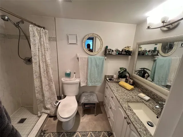 a bathroom with a granite countertop toilet and a shower curtain