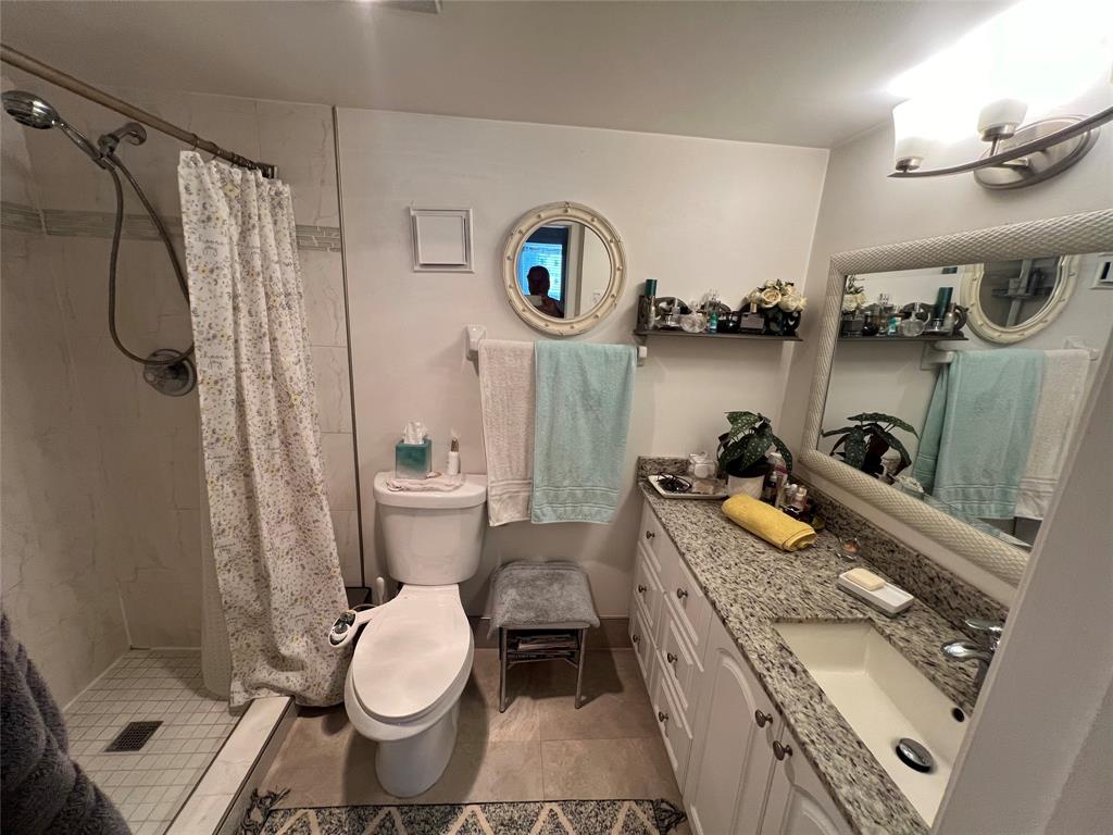 9520 Seagrape Drive, Unit 103 Davie, FL 33324 - Photo 11 of 39 a bathroom with a granite countertop toilet and a shower curtain