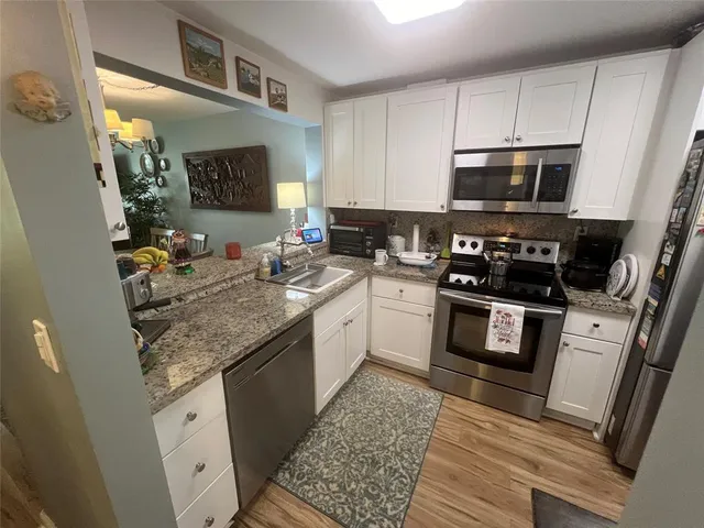 a kitchen with stainless steel appliances granite countertop a stove a sink and a microwave