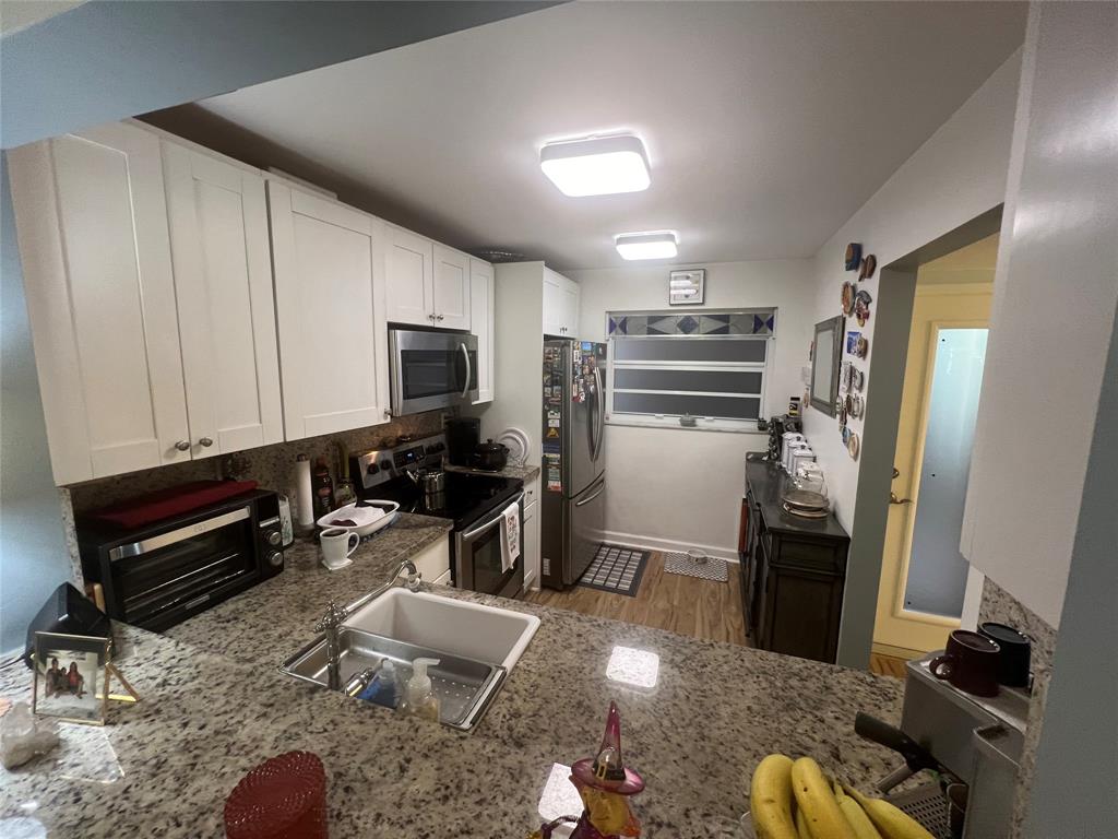 9520 Seagrape Drive, Unit 103 Davie, FL 33324 - Photo 3 of 39 a kitchen with sink refrigerator and wooden floor