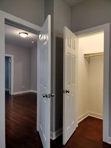 a view of an empty room with wooden floor and closet