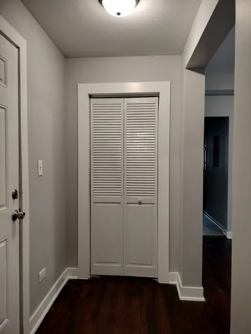an empty room with wooden floor closet and windows