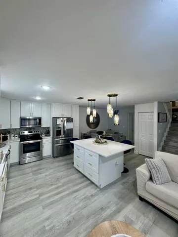 a living room with furniture kitchen view and a wooden floor