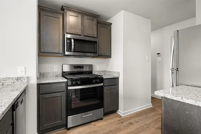 a kitchen with stainless steel appliances granite countertop a stove microwave and sink