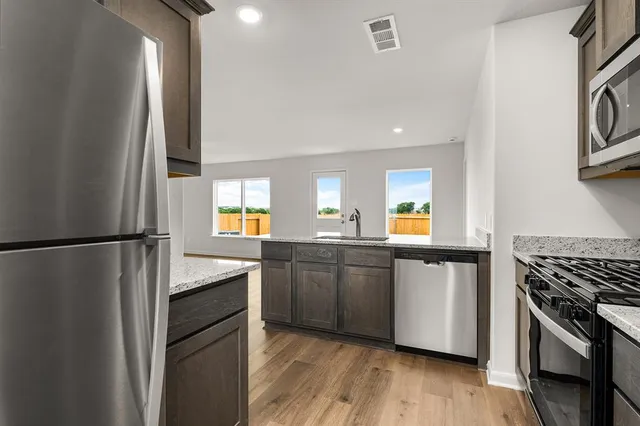 a kitchen with granite countertop a refrigerator stove and sink