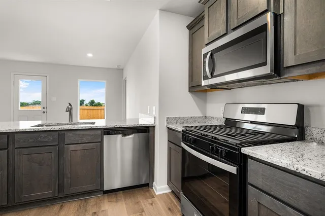 a kitchen with stainless steel appliances granite countertop a stove microwave and sink