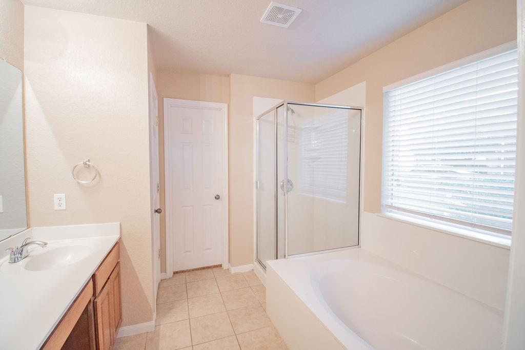 312 Pheasant Ridge Drive Round Rock, TX 78665 - Photo 19 of 34 A well-appointed bathroom features a spacious soaking tub, a separate glass-enclosed shower, and a practical single vanity.