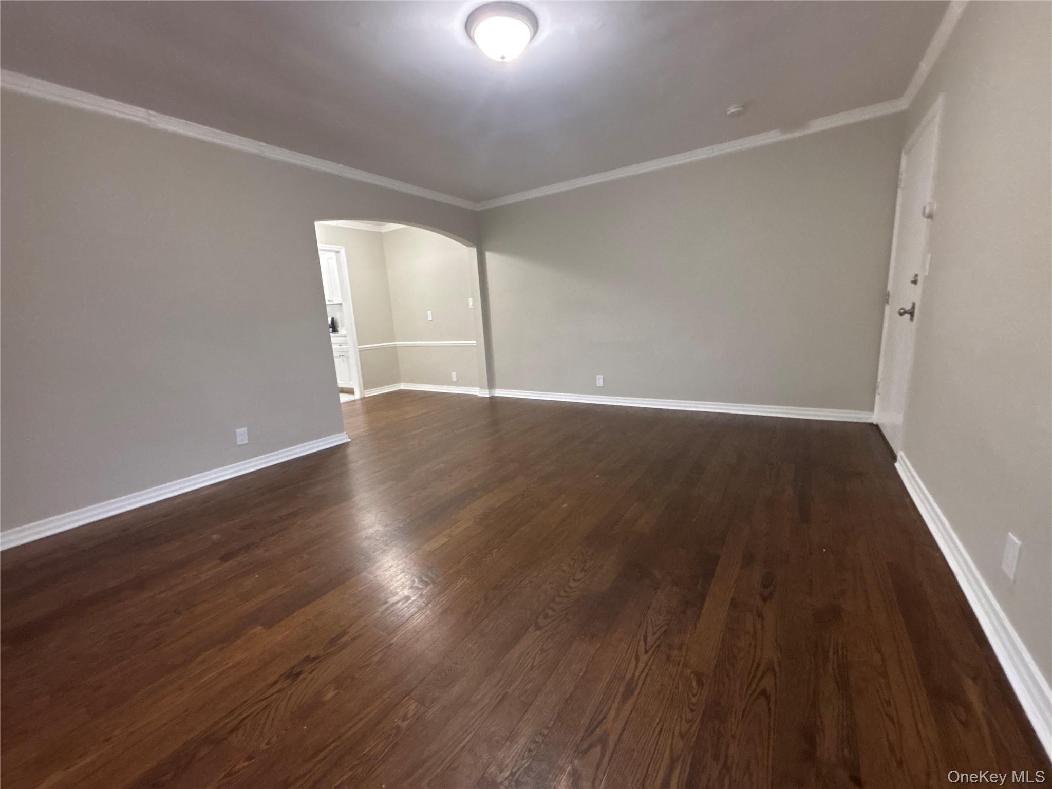 37 Spruce Street, Unit 3 Great Neck, NY 11021 - Photo 3 of 15 Unfurnished room with arched walkways, crown molding, and dark wood-type flooring