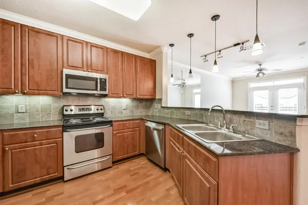 a kitchen with stainless steel appliances a refrigerator a sink and wooden cabinets