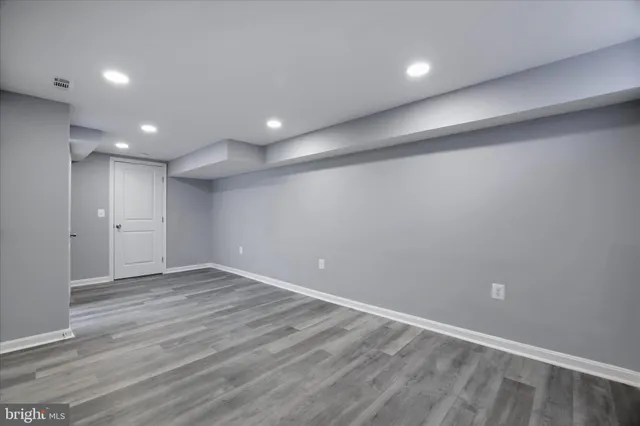 an empty room with wooden floor and natural light