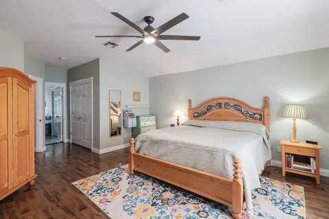 a bedroom with a bed a dresser and wooden floor