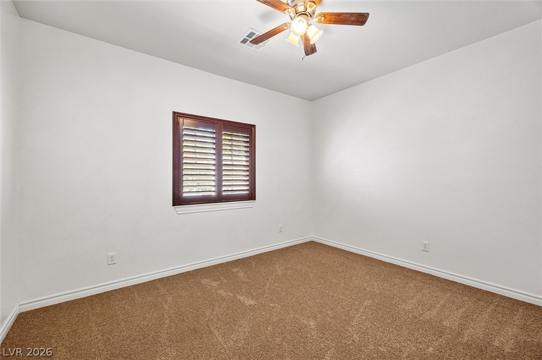 6720 Stubblefield Drive Pahrump, NV 89061 - Photo 23 of 51 A well-lit room featuring a warm ceiling fan and carpeting.