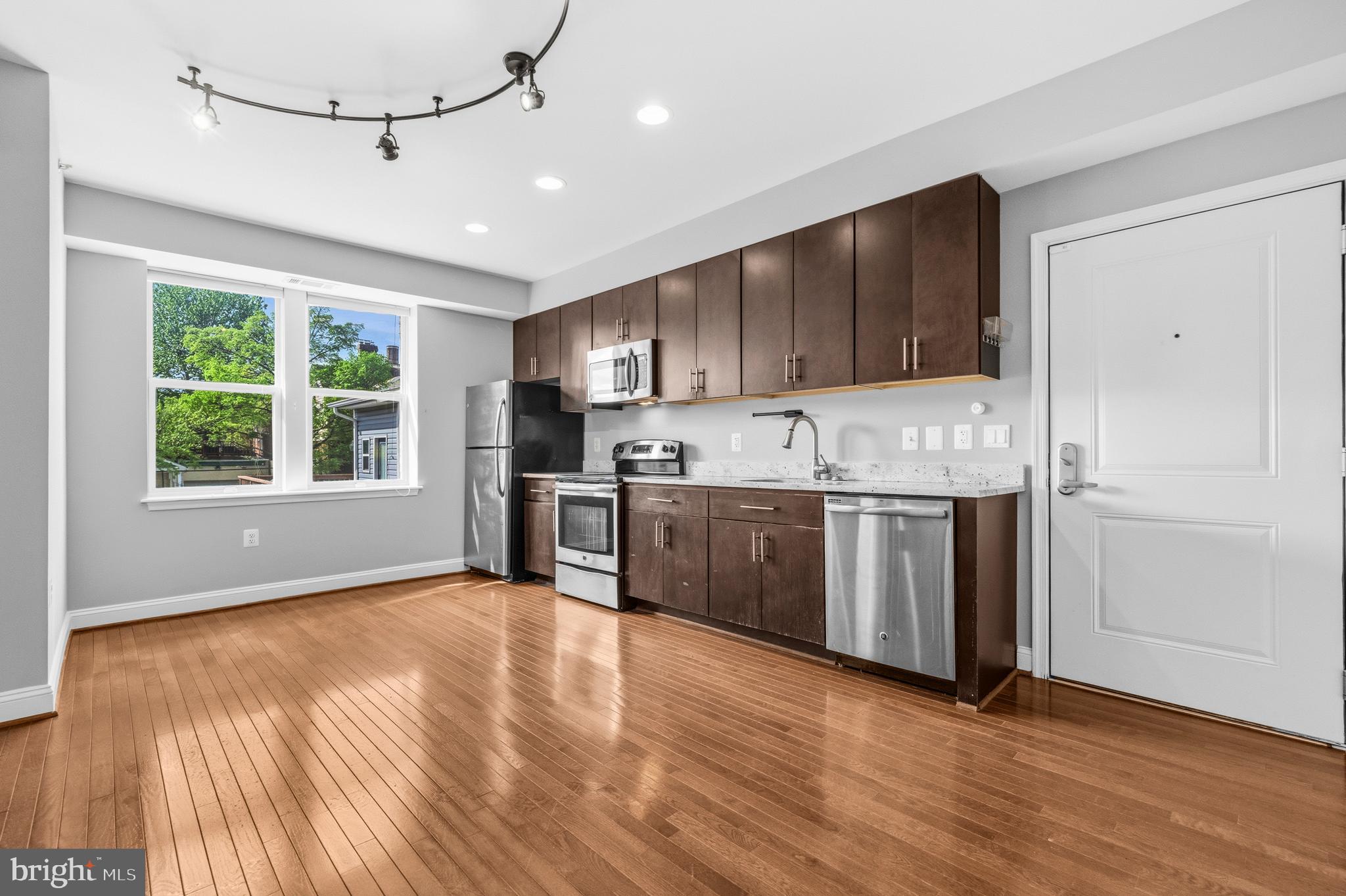 1831 2nd Street Northeast, Unit 207 Washington, DC 20002 - Photo 7 of 33 a kitchen with stainless steel appliances granite countertop a stove a sink and a refrigerator with wooden floors