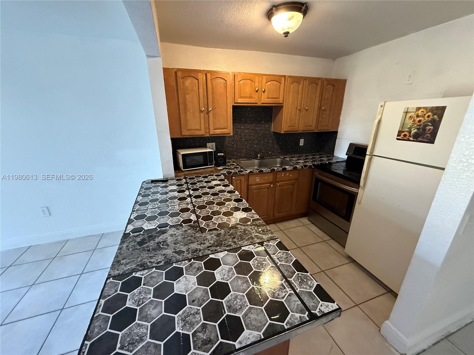 11317 Southwest 187th Terrace, Unit 4 Miami, FL 33157 - Photo 2 of 7 a kitchen with granite countertop a refrigerator and a stove