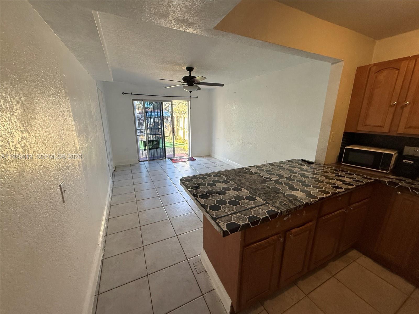 11317 Southwest 187th Terrace, Unit 4 Miami, FL 33157 - Photo 5 of 7 a kitchen with kitchen island granite countertop a sink stove and cabinets