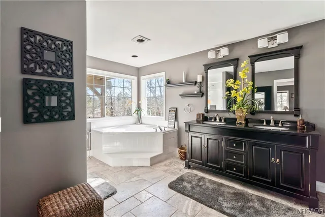 a spacious bathroom with a double vanity sink a mirror and a bathtub