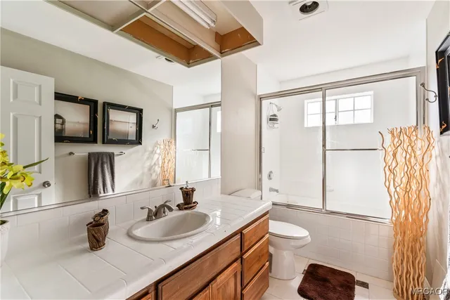 a bathroom with a granite countertop sink toilet a mirror and shower