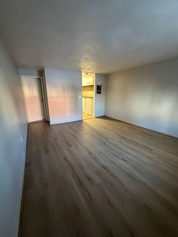 27 Gordon Street, Unit 105 Framingham, MA 01702 - Photo 6 of 7 a view of empty room with wooden floor and fan