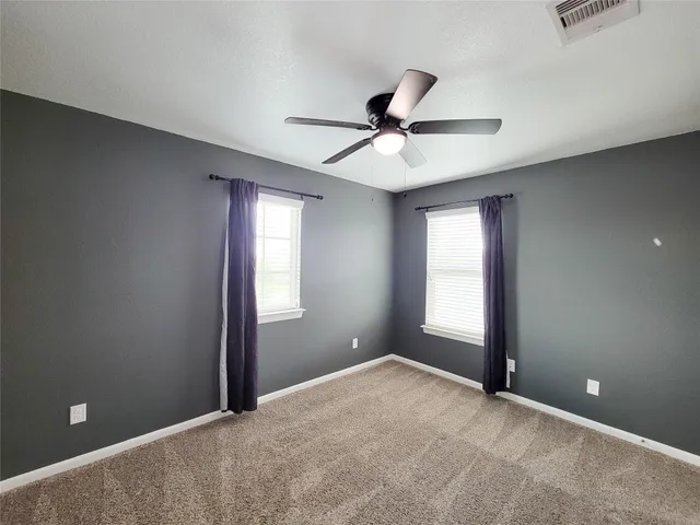 a view of empty room with window and ceiling fan