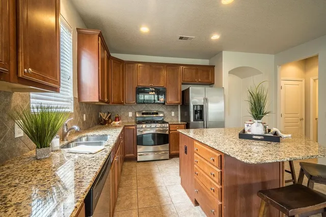 a kitchen with stainless steel appliances granite countertop a sink stove and refrigerator