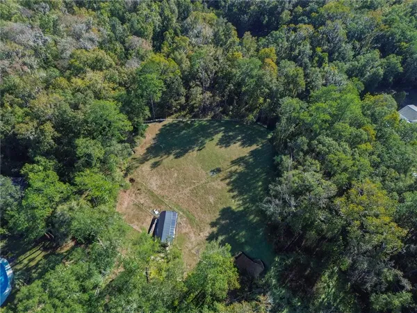 an aerial view of residential house with outdoor space and trees all around