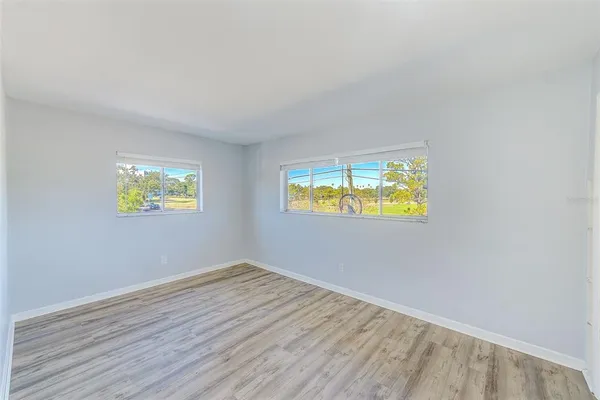 a view of an empty room with window and wooden floor