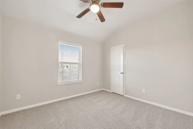 an empty room with a window and ceiling fan
