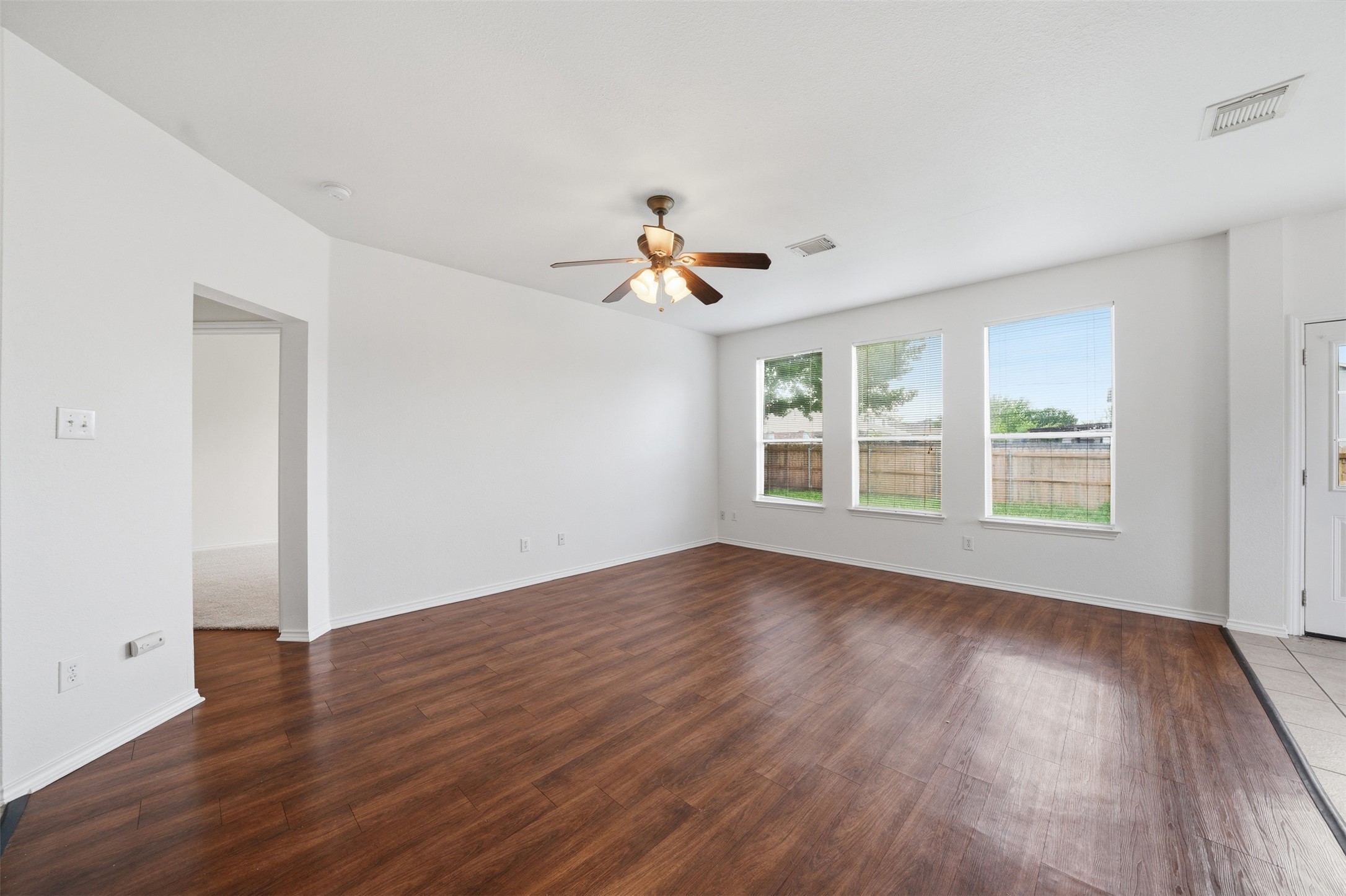 118 Invierno Street Kyle, TX 78640 - Photo 13 of 37 Rich hardwood-style flooring flows through this well-lit open-concept living area.