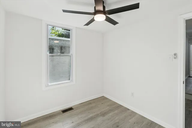an empty room with wooden floor fan and windows