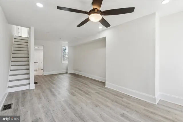 an empty room with wooden floor closet fan and windows