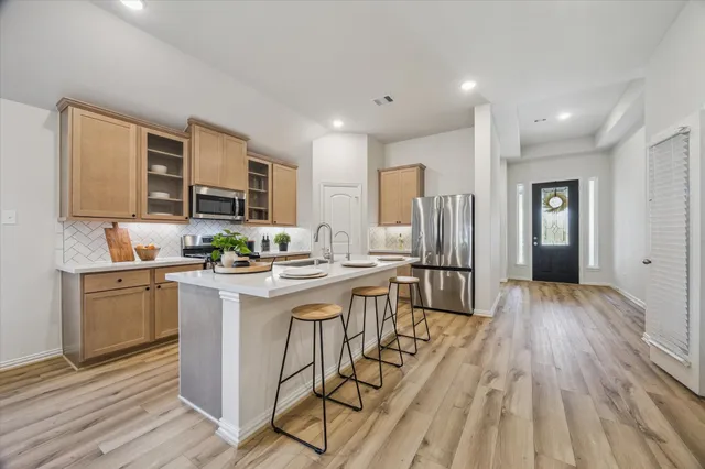 a kitchen with stainless steel appliances granite countertop a refrigerator oven a sink dishwasher and white cabinets with wooden floor