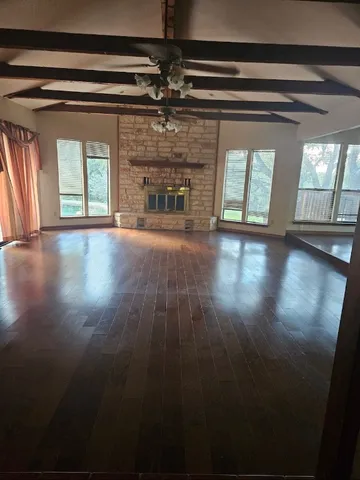 a view of empty room with wooden floor and fireplace