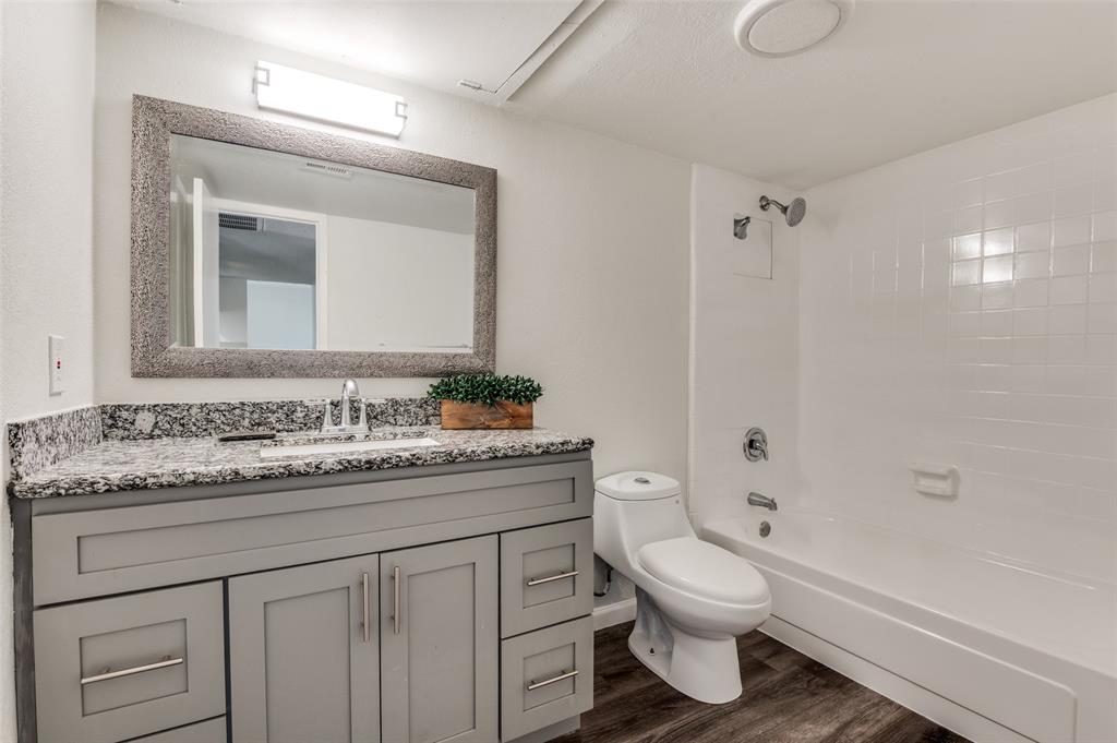 4859 Cedar Springs Road, Unit 254 Dallas, TX 75219 - Photo 2 of 14 a bathroom with a granite countertop toilet a sink and a mirror