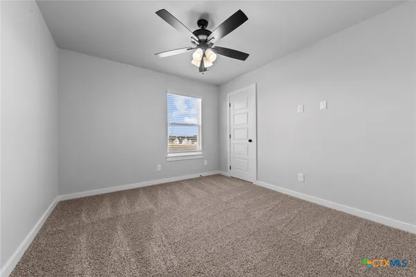 an empty room with a window and a fan
