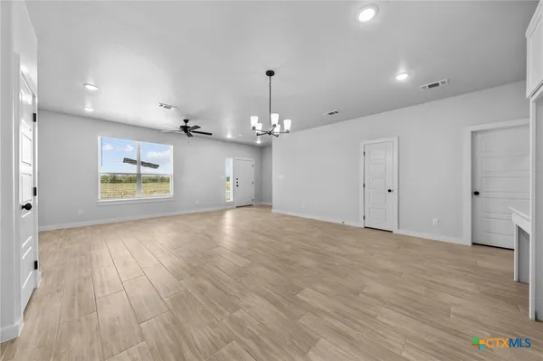a view of an empty room with window and wooden floor