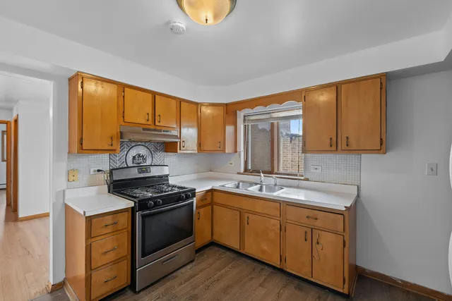 a kitchen with stainless steel appliances granite countertop a stove a sink and a microwave