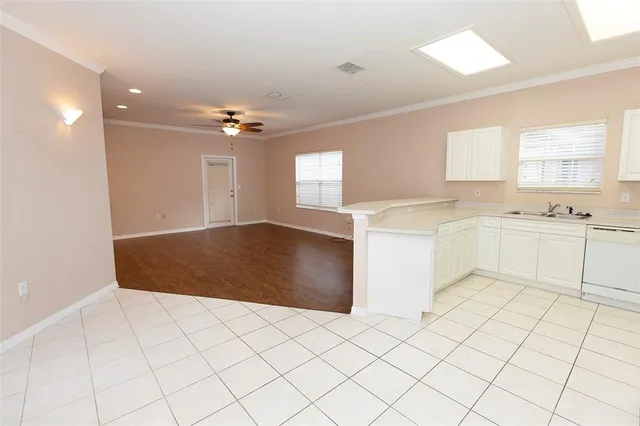 a large white kitchen with a sink and dishwasher a stove top oven with white cabinets