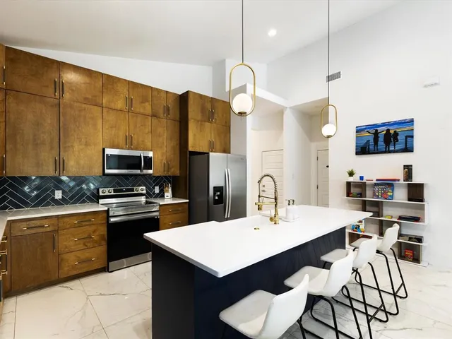 a kitchen with a sink a kitchen island a stove and a refrigerator
