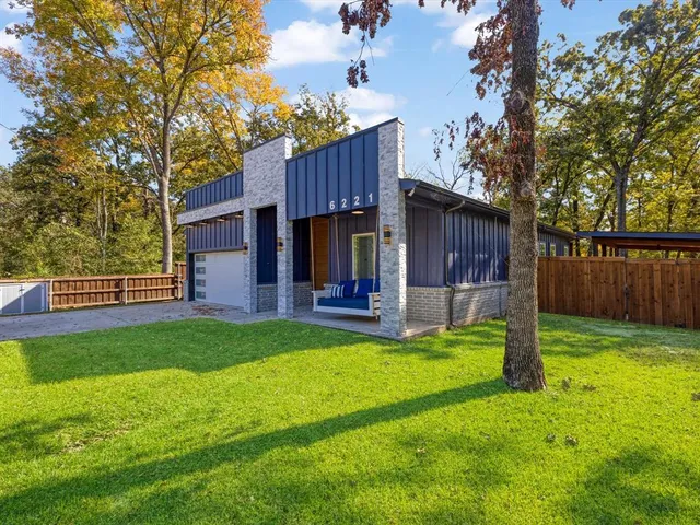 a view of a house with backyard and wooden fence