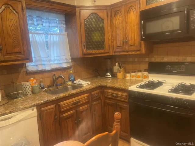 a kitchen with granite countertop a sink a stove and cabinets