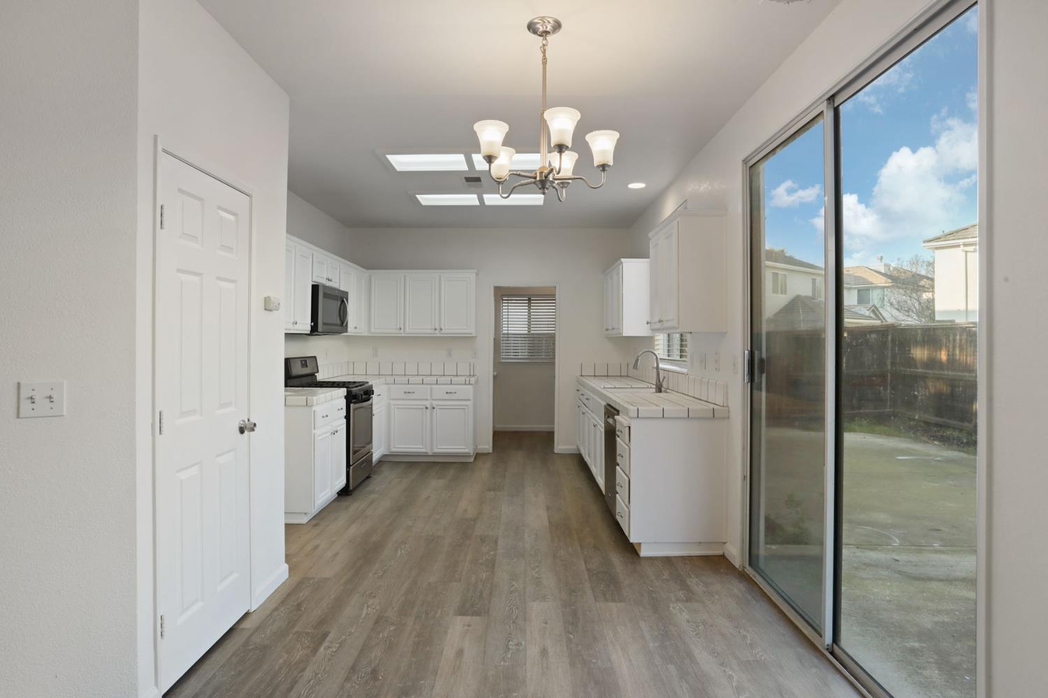 4882 Timepiece Circle Stockton, CA 95219 - Photo 18 of 43 a kitchen with stainless steel appliances granite countertop a refrigerator a sink dishwasher a stove and white cabinets with wooden floor