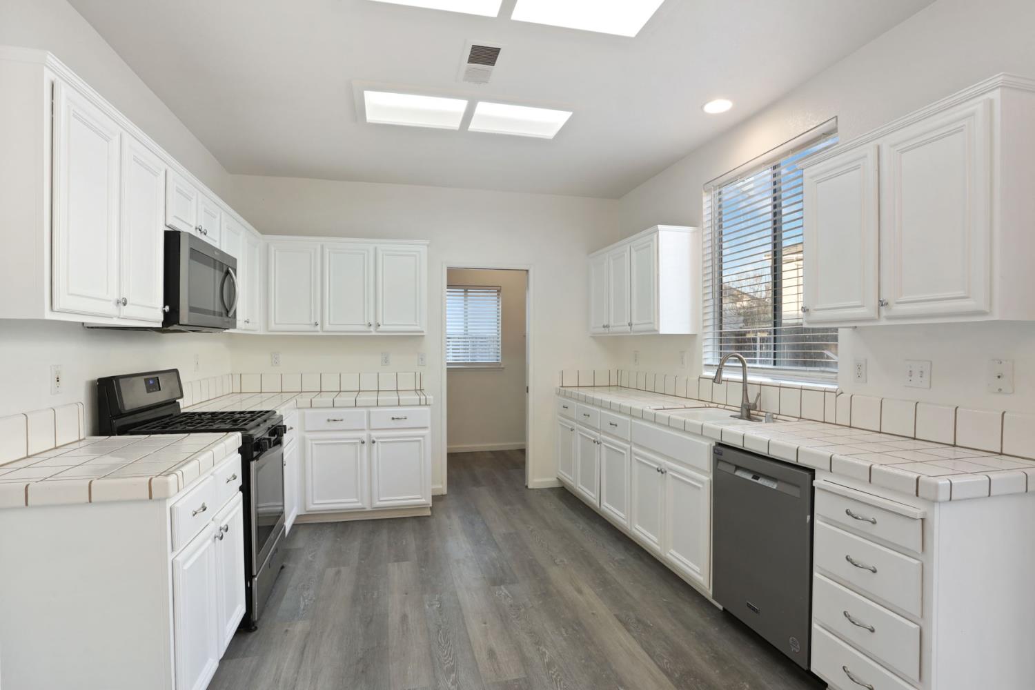 4882 Timepiece Circle Stockton, CA 95219 - Photo 21 of 43 a kitchen with white cabinets appliances a sink and a window