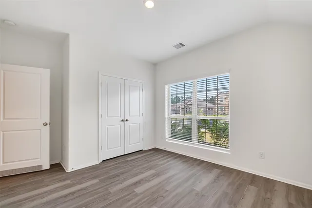 an empty room with wooden floor and windows