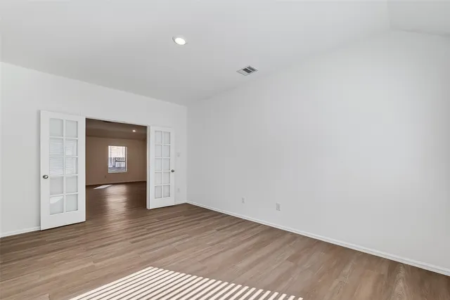 a view of empty room with wooden floor and window
